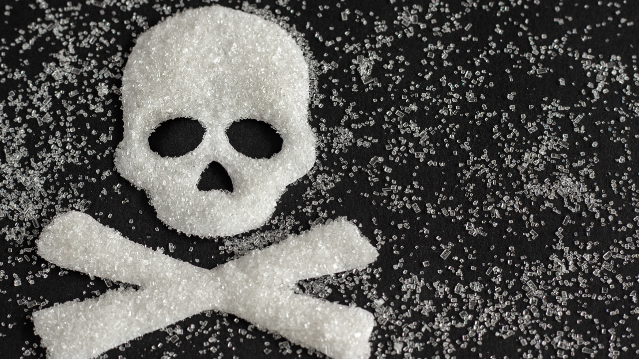 cane sugar spread out all over a black mat with a skull and bones image created out of the sugar