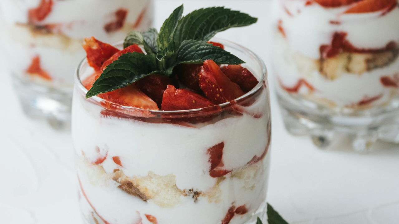 strawberry shortcakes in glass cups topped with strawberry mixture and mint leaves