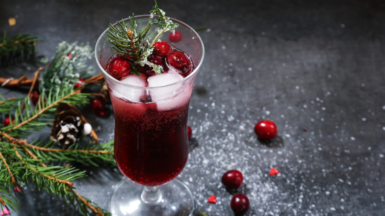 holiday iced cranberry drink pictured next to fallen cranberries and christmas tree branches