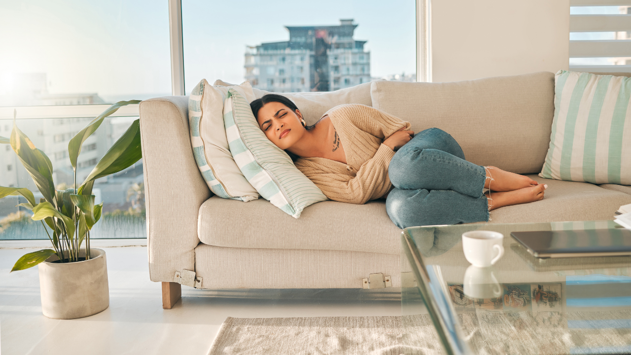 lady laying on the couch holding her stomach due to stomach issues
