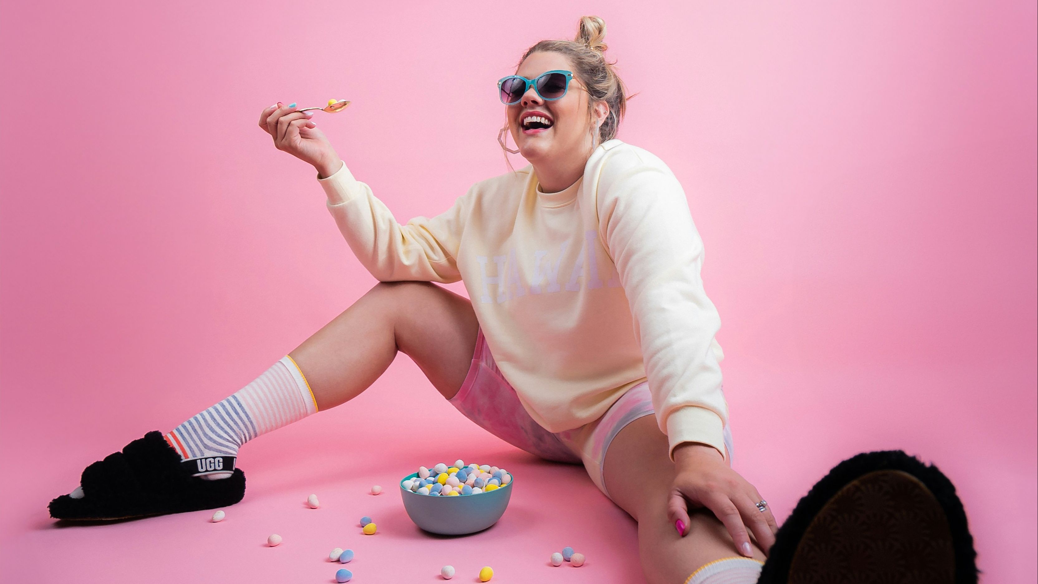 Women on pink background wearing sunglasses, laughing 