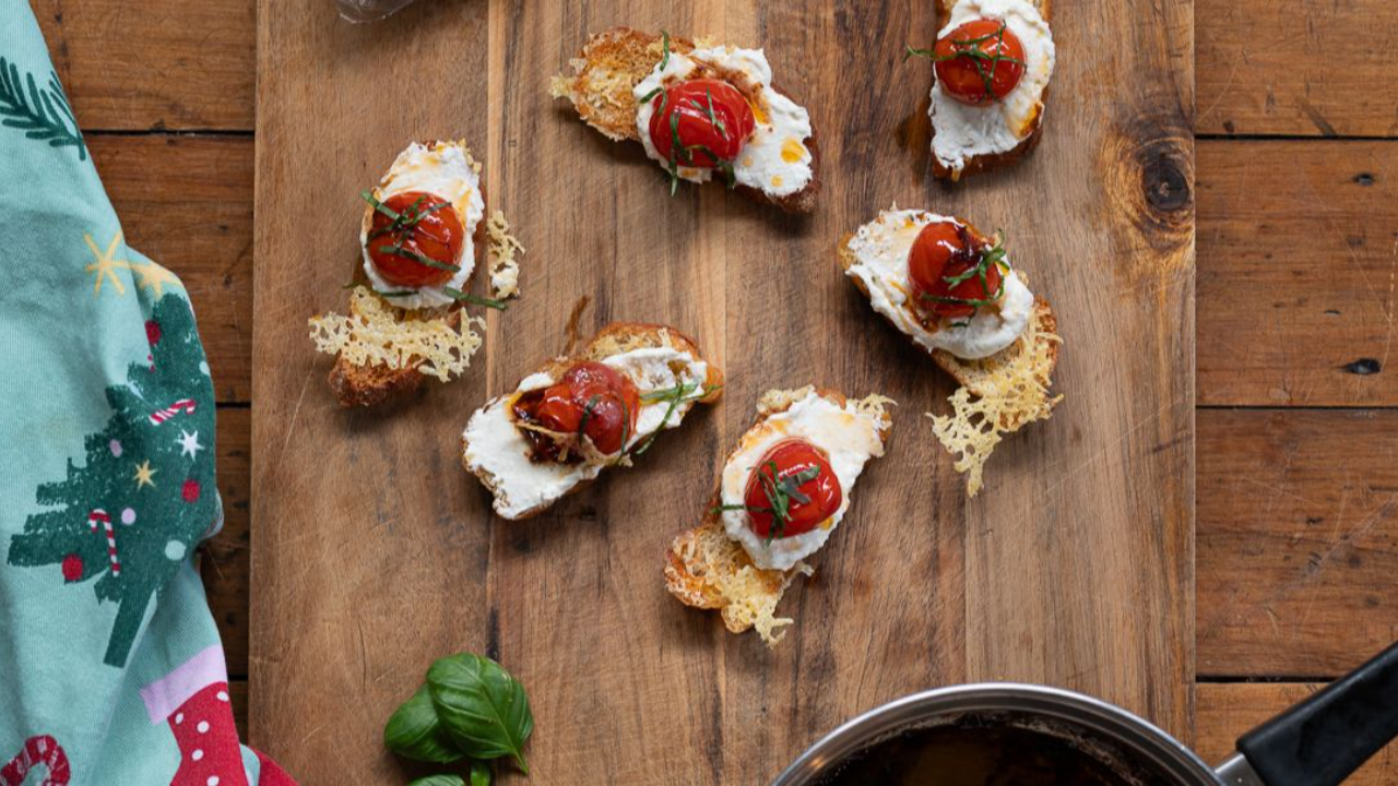crispy crostini topped with whipped feta creamy spread and slow roasted cherry tomatoes garnished with fresh basil