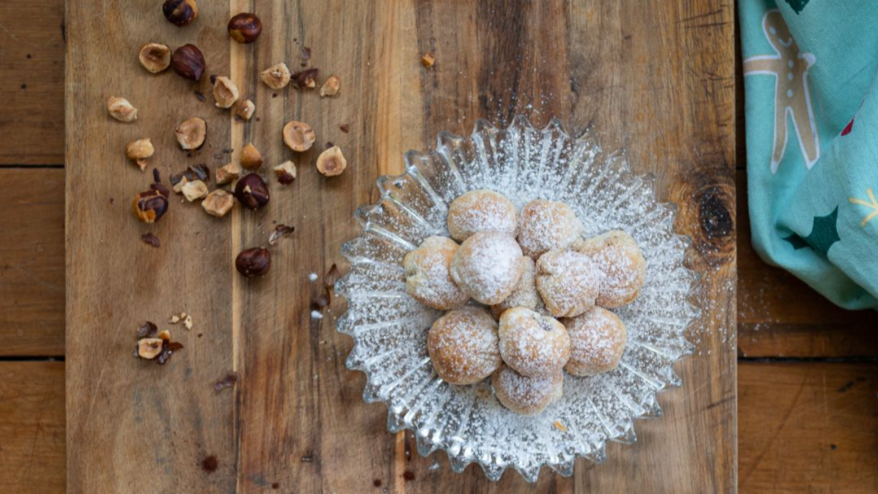 golden puff pastry balls dusted with icing sugar filled with chocolate hazelnut spread like ferrero rocher on serving plate