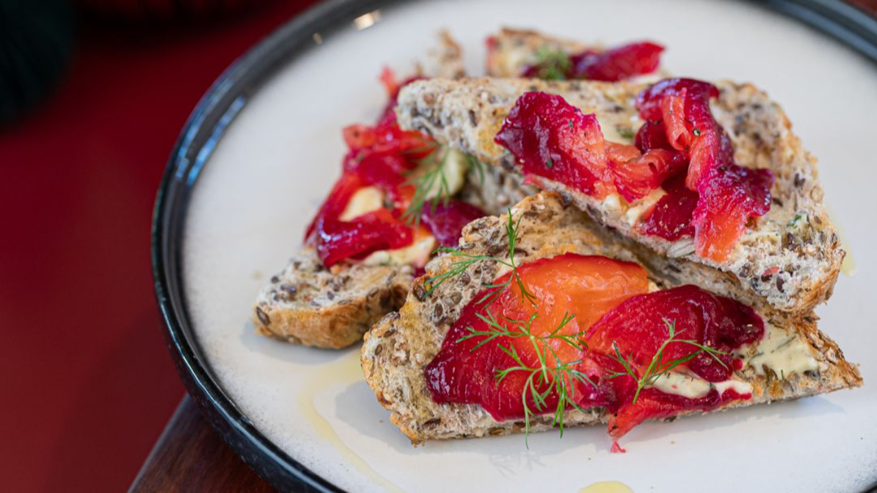 vibrant pink beetroot cured salmon sliced thinly on toast with fresh dill