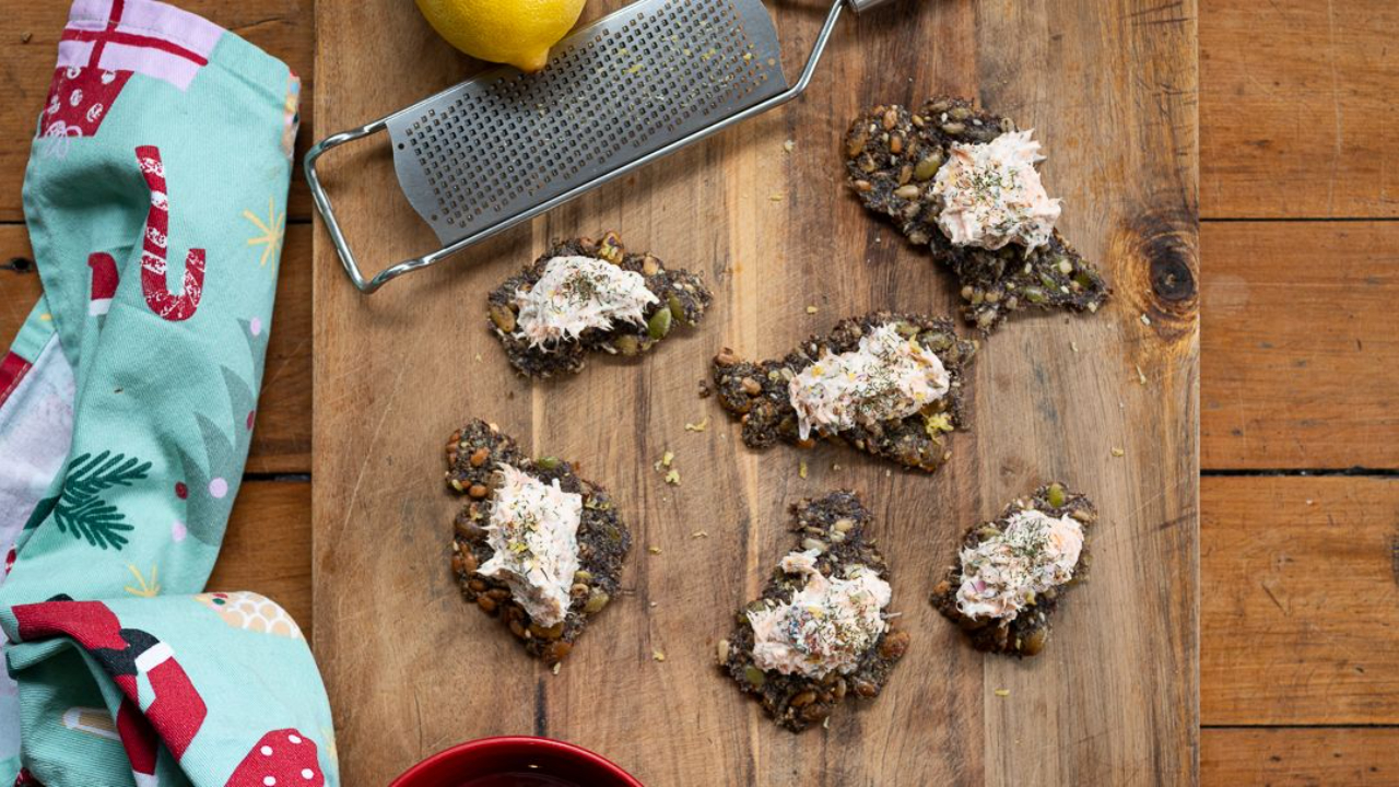 salmon rillettes spread with capers and dill on homemade seed crackers garnished with lemon zest