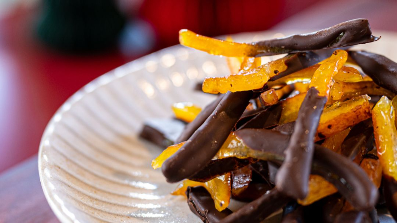 candied orange peel strips half dipped in dark chocolate arranged on a plate
