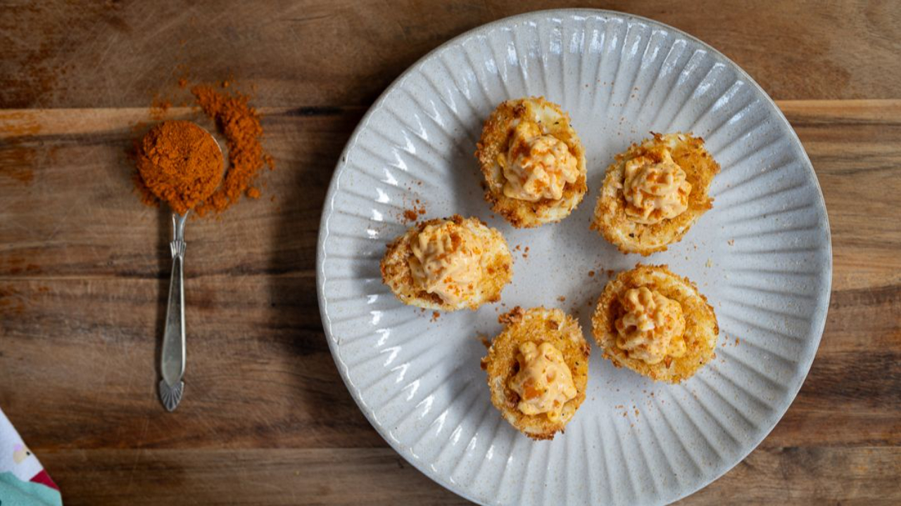 golden crispy air fried devilled eggs with panko coating filled with creamy curried yolk mixture on serving plate