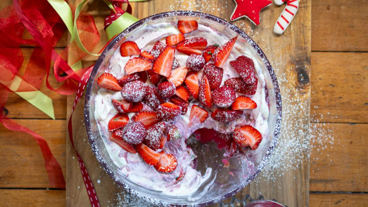 layered trifle with jelly sponge apricots greek yoghurt and strawberries in glass bowl