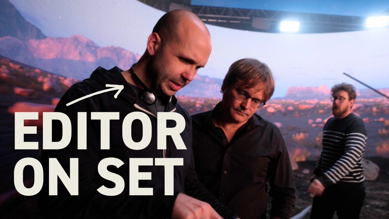 A video editor on a film set, looking at camera equipment with a director, demonstrating collaboration between production and post-production.