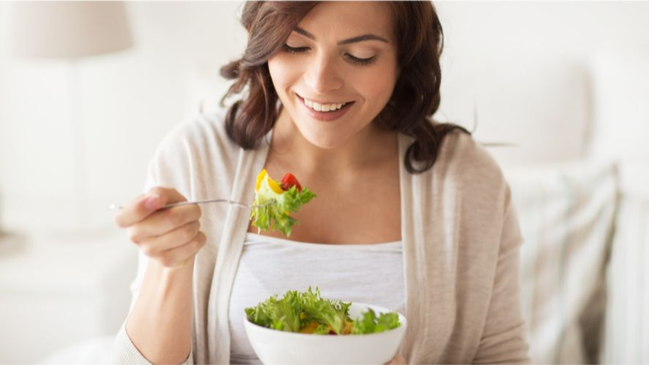 Woman practicing mindful eating while enjoying a fresh salad.