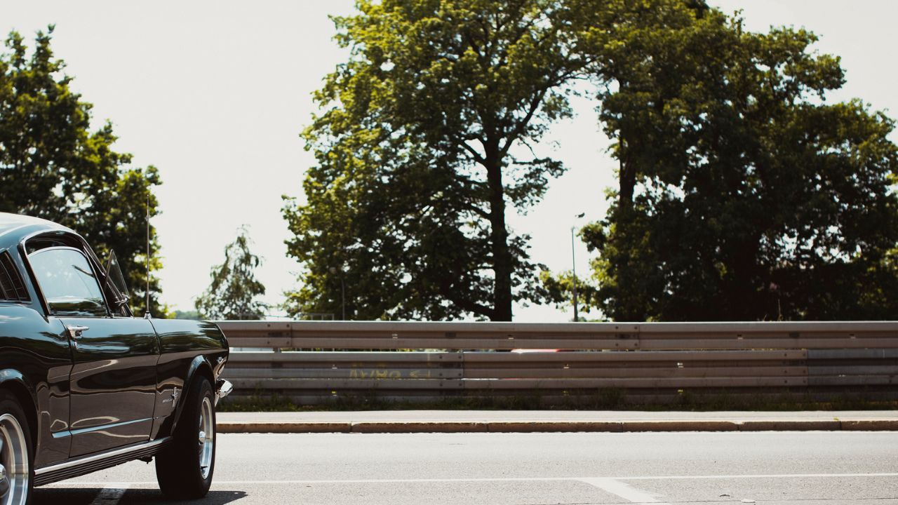 black car in empty parking lot by trees