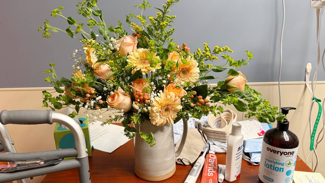 flower arrangement next to a hospital bed with a walker nearby and toiletries