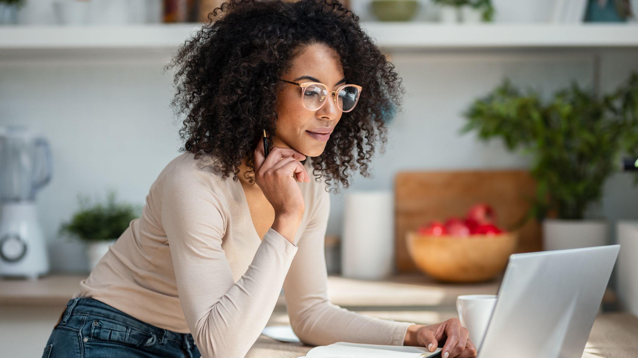 Woman working with laptop in the kitchen at home.
