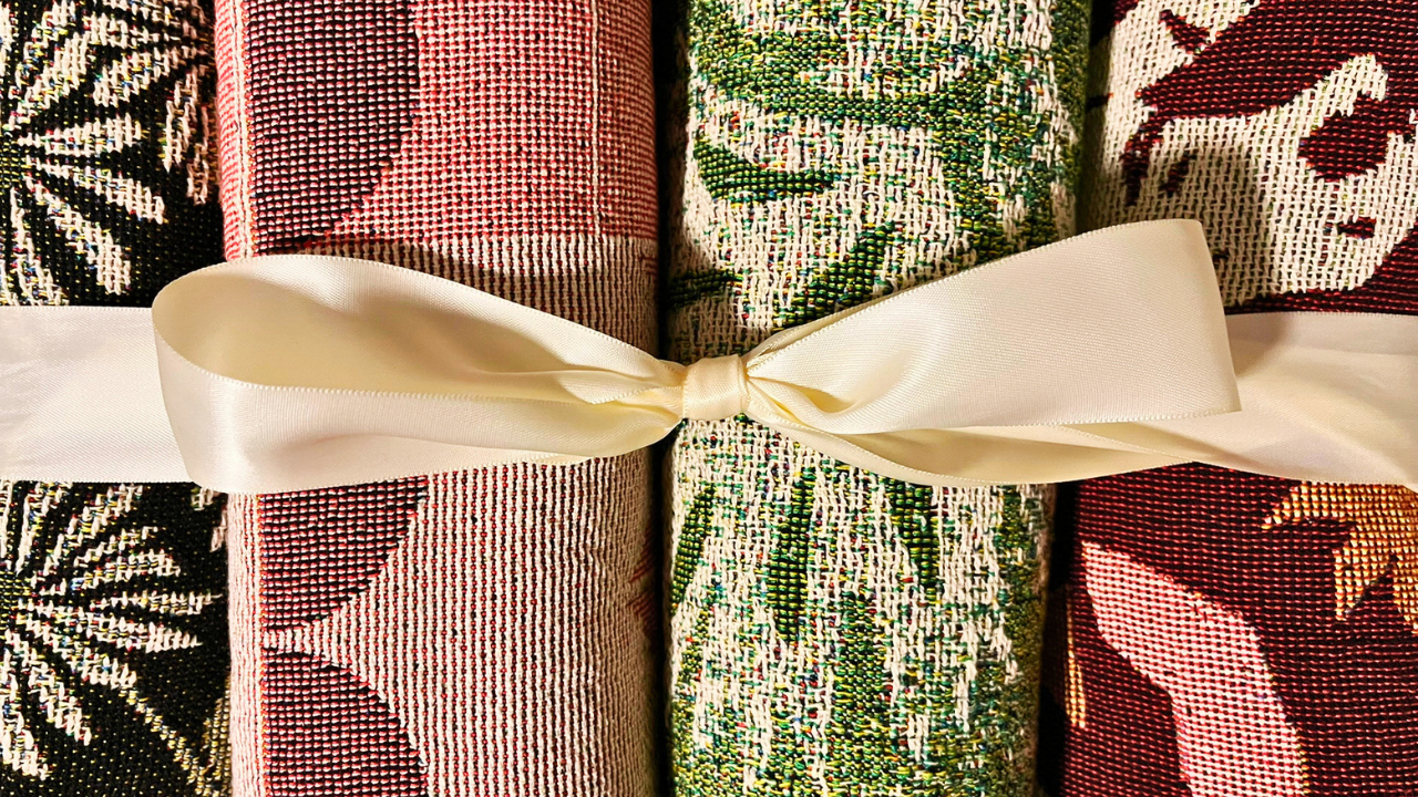 Detail of a collection of red and green blankets tied with a cream ribbon.