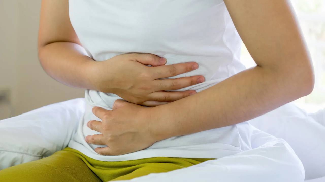 woman sitting down holding both hands on stomach