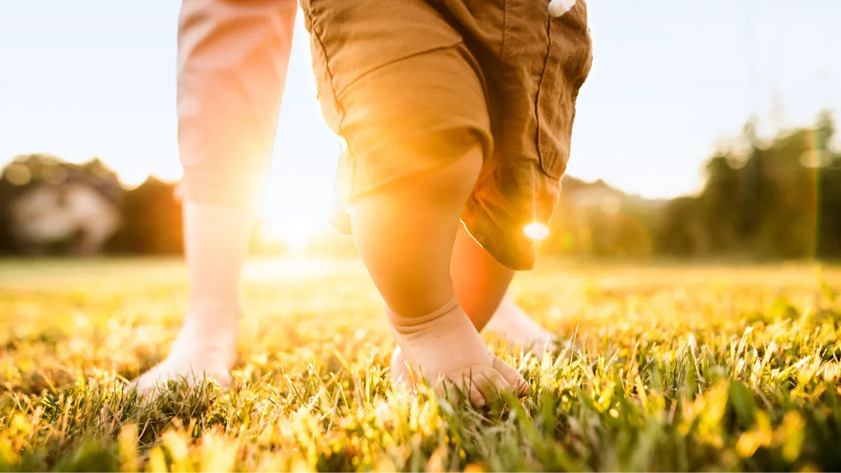mom and toddler walking barefoot in grass