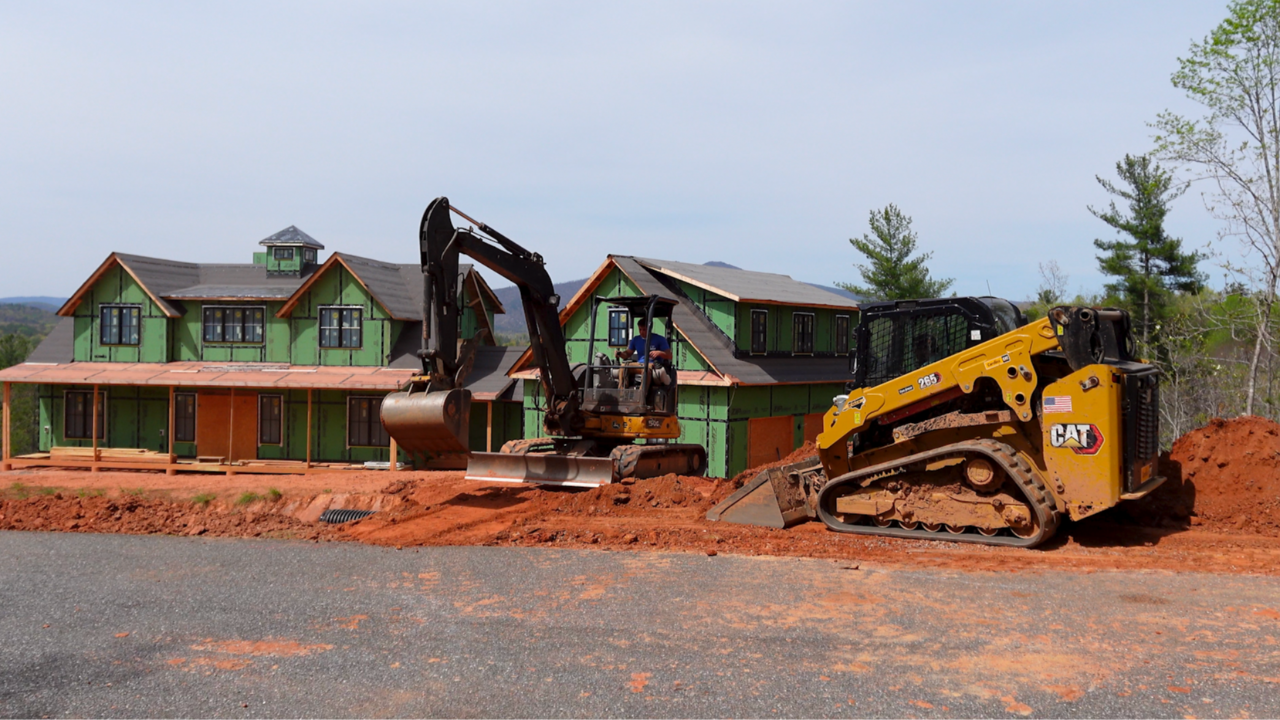 Project manager and operator working with excavator and skid steer on a residential construction site