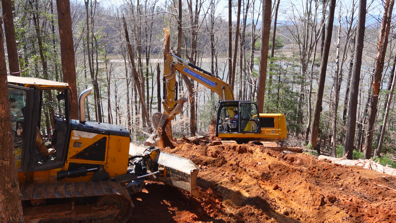 Bulldozer and excavator moving dirt to build a driveway