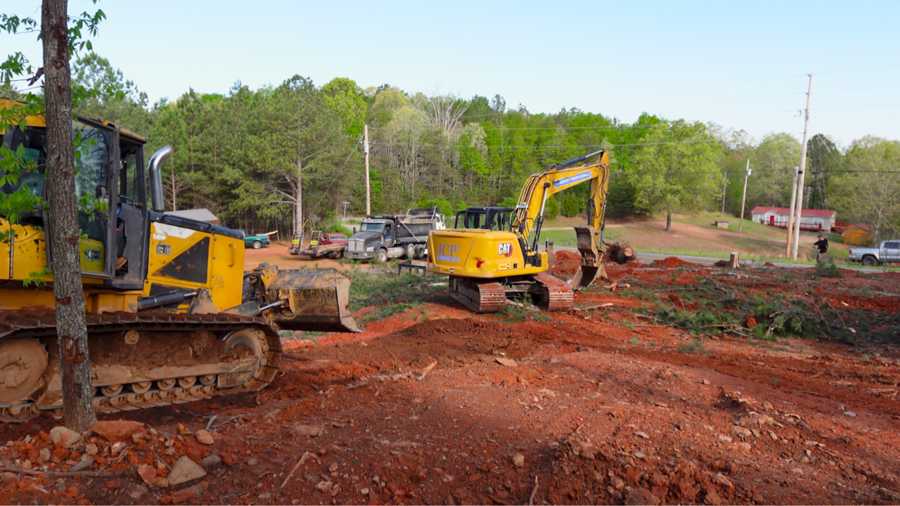 Excavator and bulldozer clearing and grading dirt on a residential job site