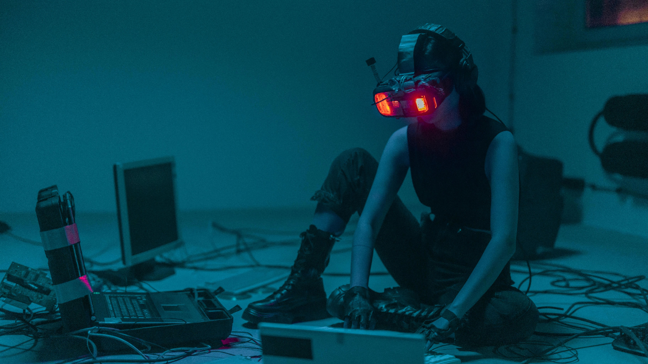 A woman wearing a VR headset sits on the floor at Intimata, Oxford, surrounded by computers and cables, illustrating the integration of technology in modern sex and relationship therapy.