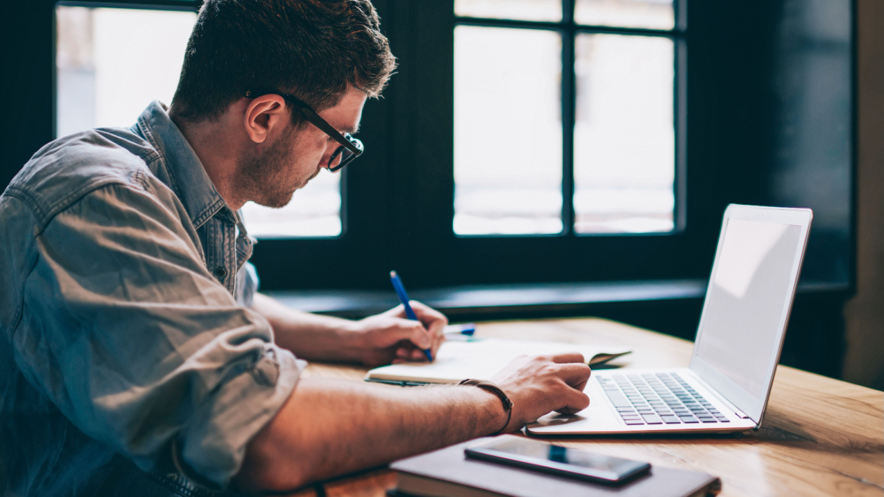 Focused professional working on a laptop and taking notes for nonprofit grant application budget planning, effective strategies for securing funding.