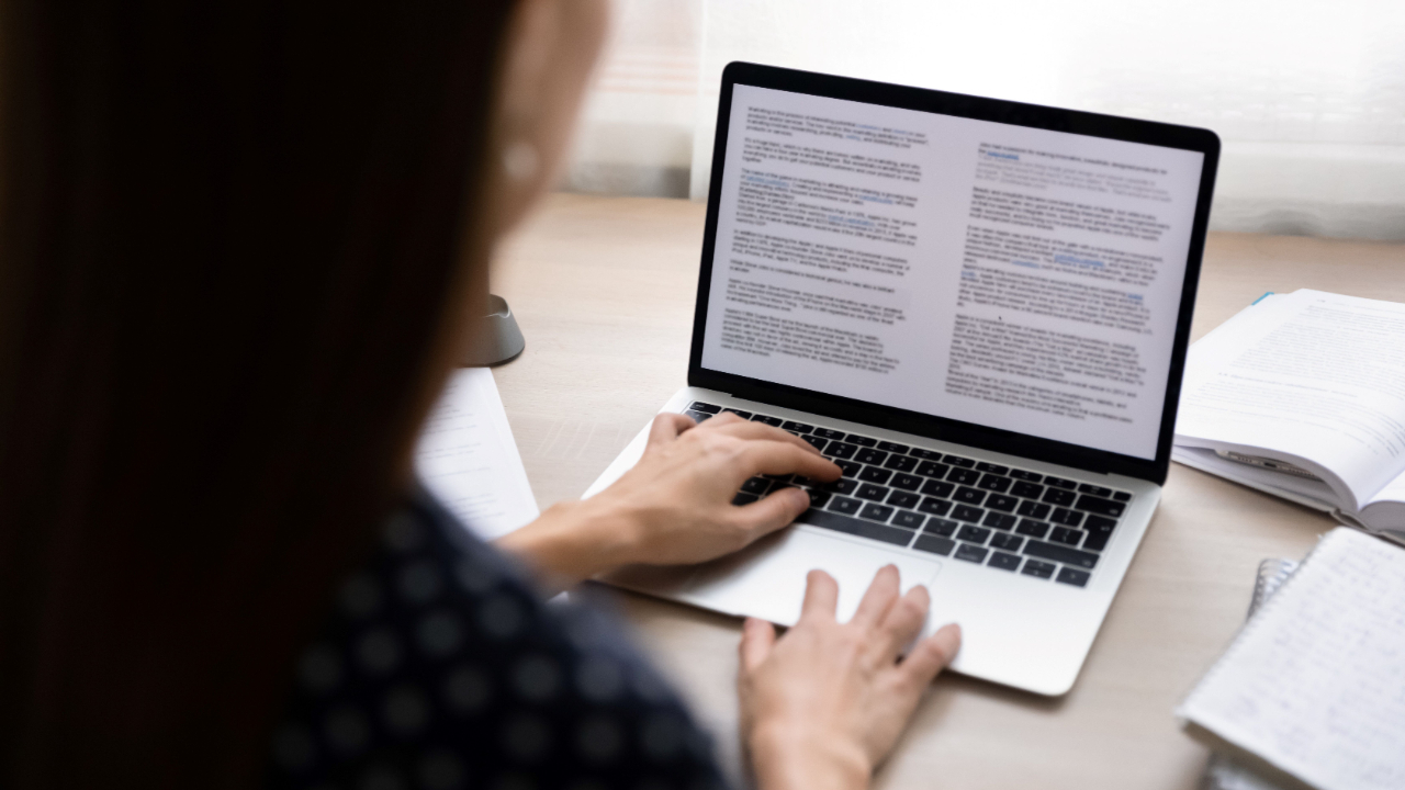 Person drafting a grant proposal on a laptop, focusing on collecting beneficiary data using surveys, technology, and qualitative insights for data-driven grant writing strategies.