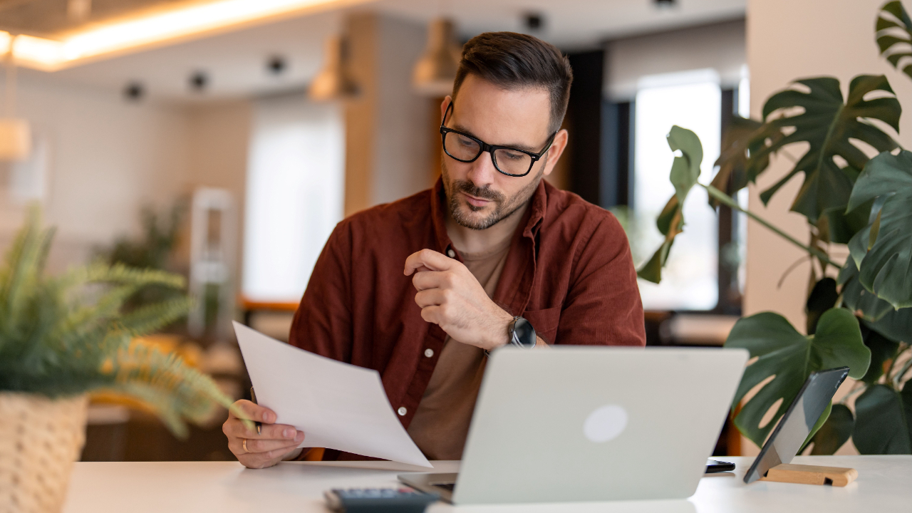 A focused professional reviewing documents while working on a laptop, providing expert tips on how to answer the 'What will you do and why?' question in nonprofit grant applications.