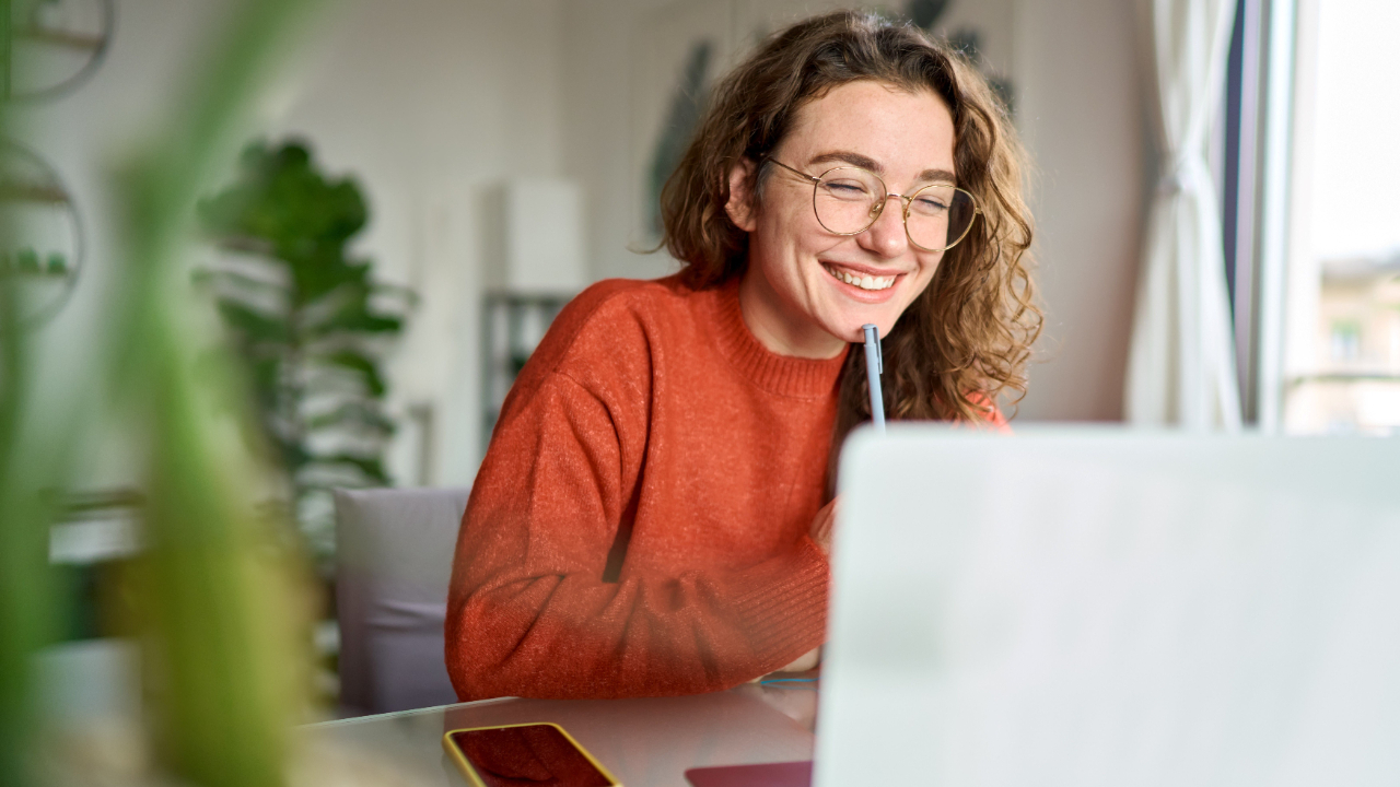 A smiling professional reviewing project metrics on a laptop, focused on evaluating grant application progress and success strategies.