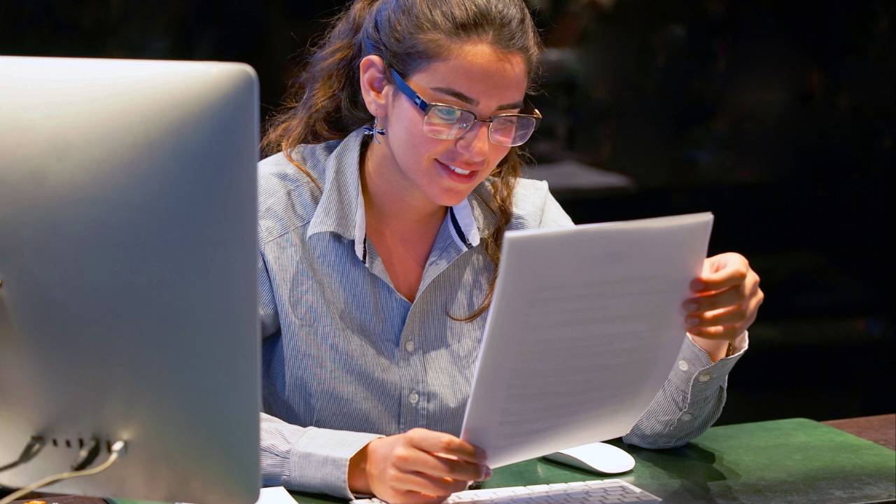 A professional woman reviewing documents at a computer, representing effective hiring of a grant writer for nonprofit organizations.