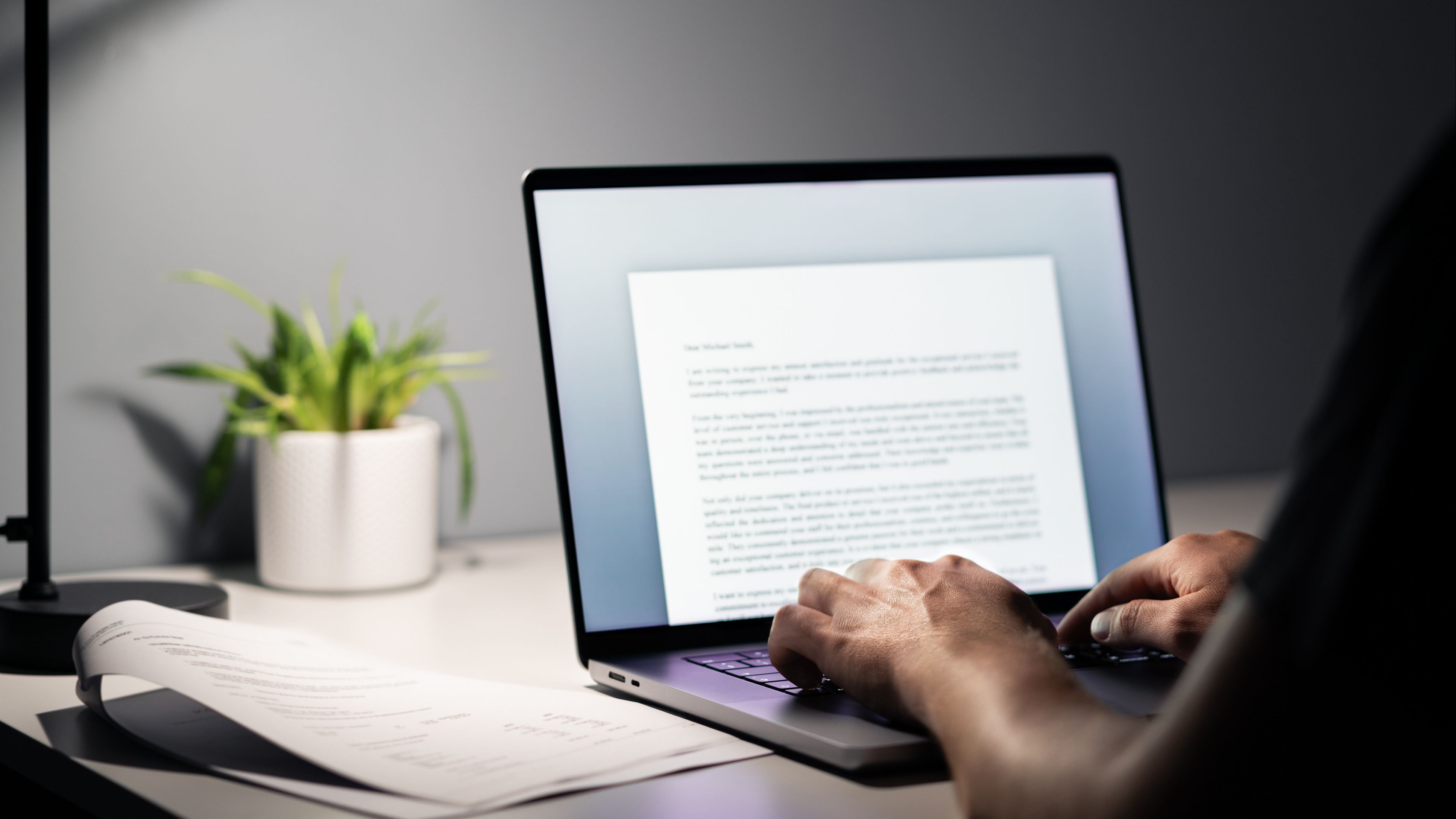 Writing a nonprofit grant proposal on a laptop, focusing on differences between clients, customers, and beneficiaries in grant writing strategies.