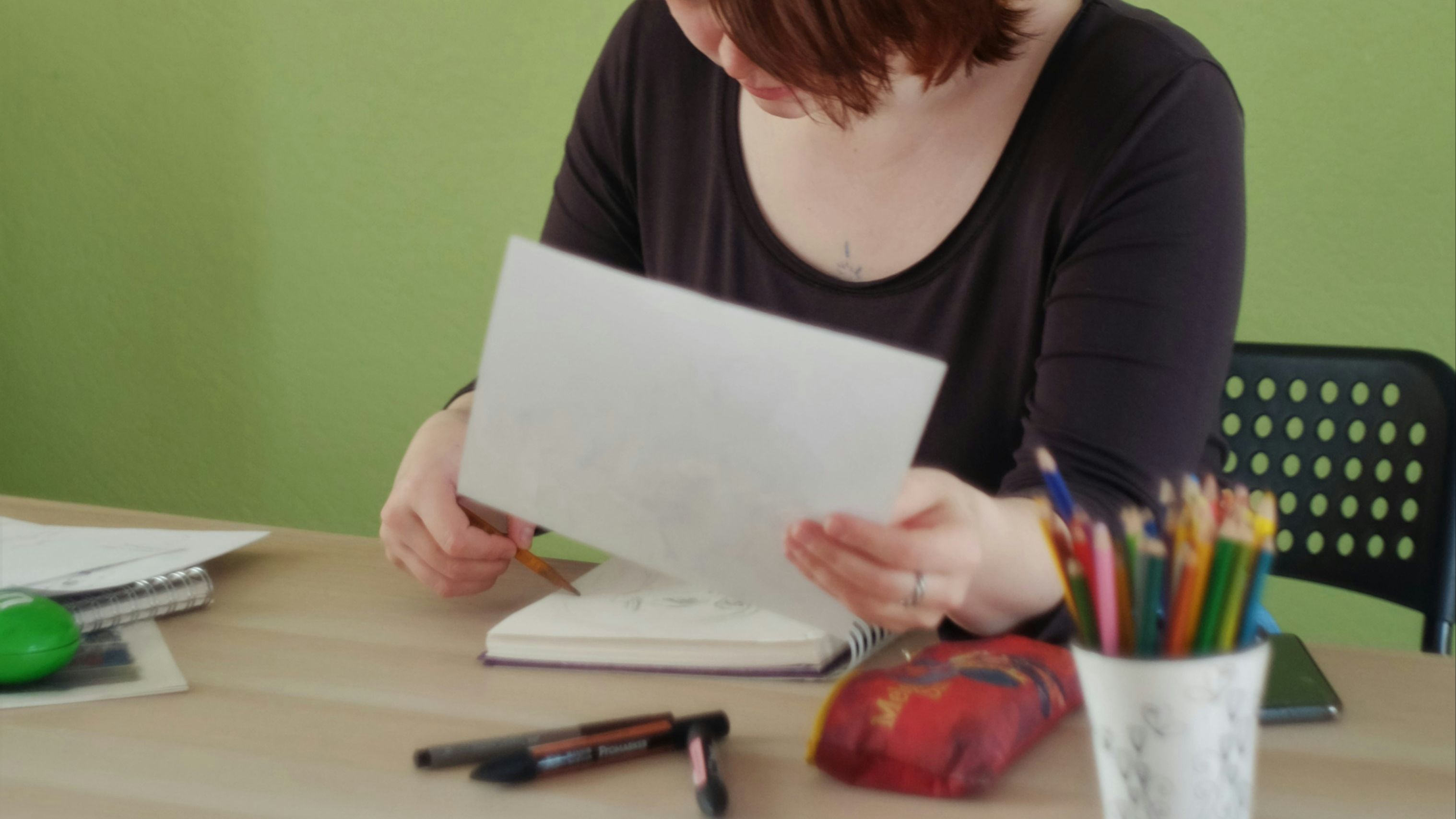 Person calculating cost of owning a parrot with bird perched nearby looking at paperwork