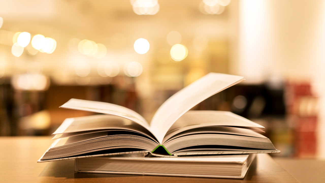 Open books on a library table with a softly blurred background, representing the extensive pre-internet research that contributed to restoring Jefferson Davis’s U.S. citizenship.