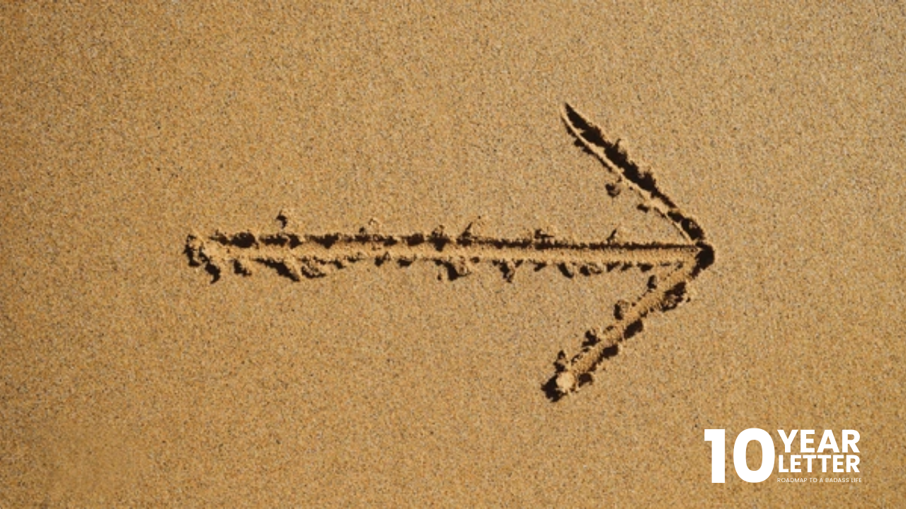 Arrow drawn in sand pointing forward, symbolizing intentional direction.