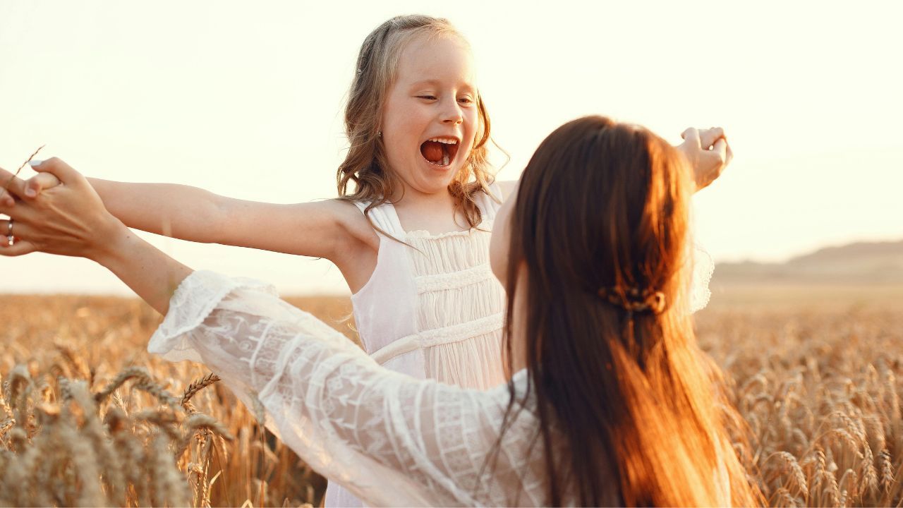 Mamă care se joacă pe covor cu un copil mic folosind jucării simple pentru stimularea limbajului și a comunicării prin joc.