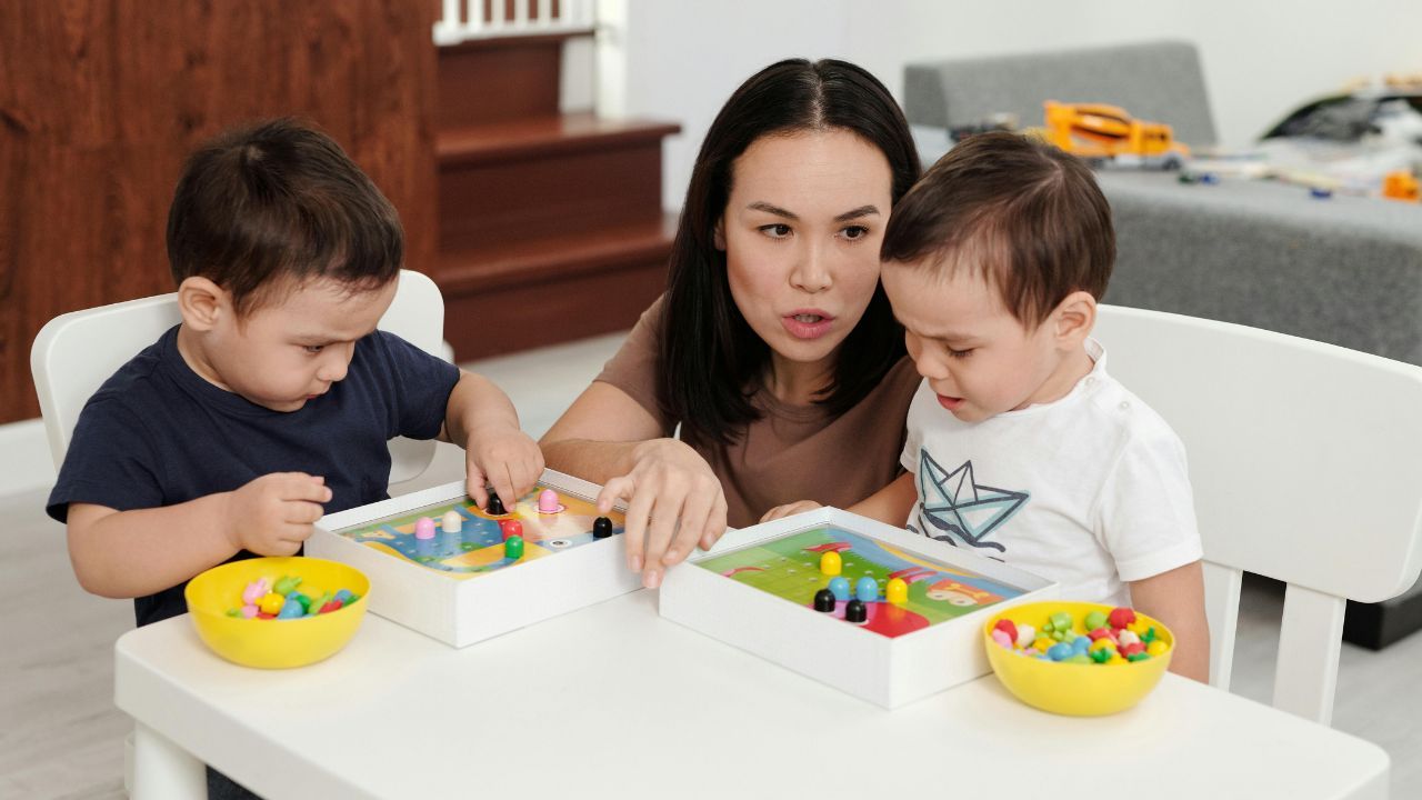 Mamă sau terapeut care se joacă pe covor cu un copil mic pentru dezvoltarea limbajului, atenției și conexiunii emoționale.