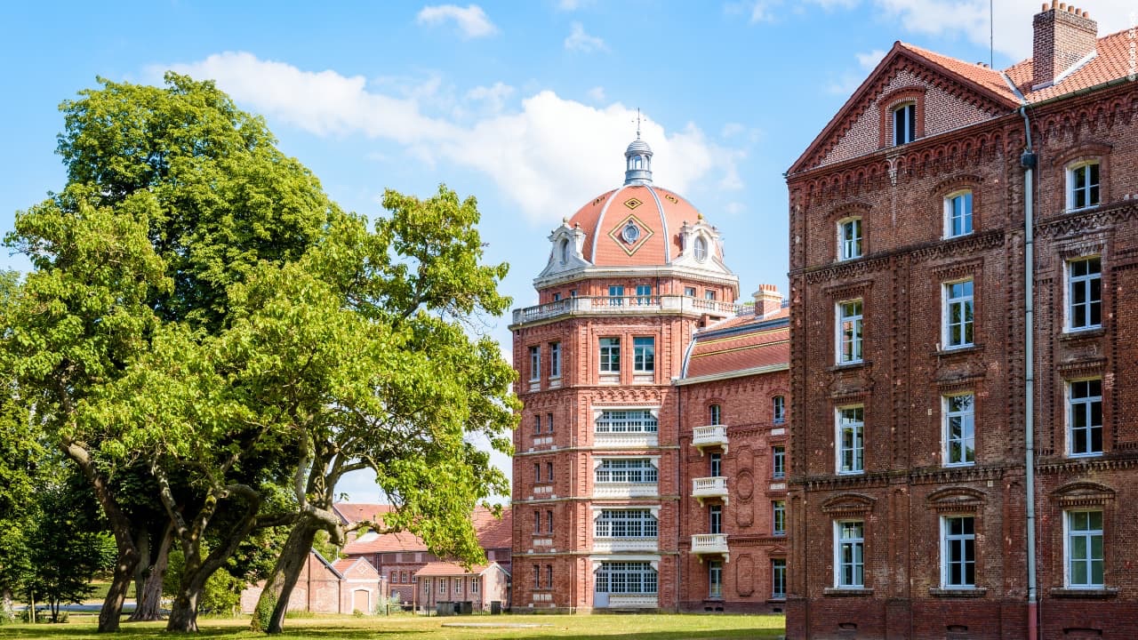 Familistère van Guise met plein en bomen op de voorgrond