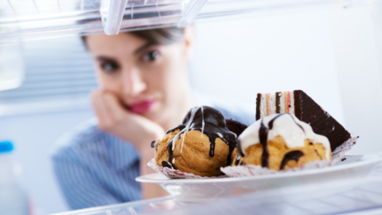 Woman looking at cakes and pastries experiencing sugar cravings