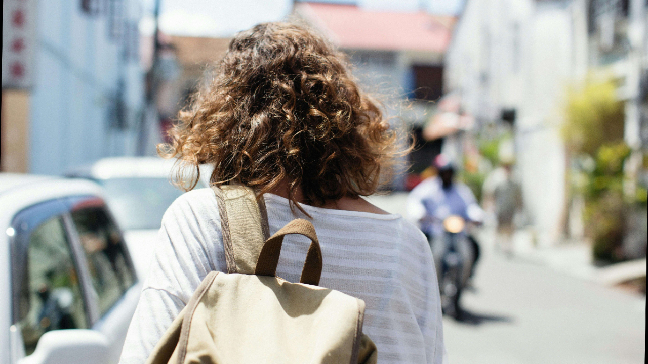 Woman carrying a backpack while walking down a busy street | therapy for expats | international therapist | expat therapy online | Netherlands | England | France