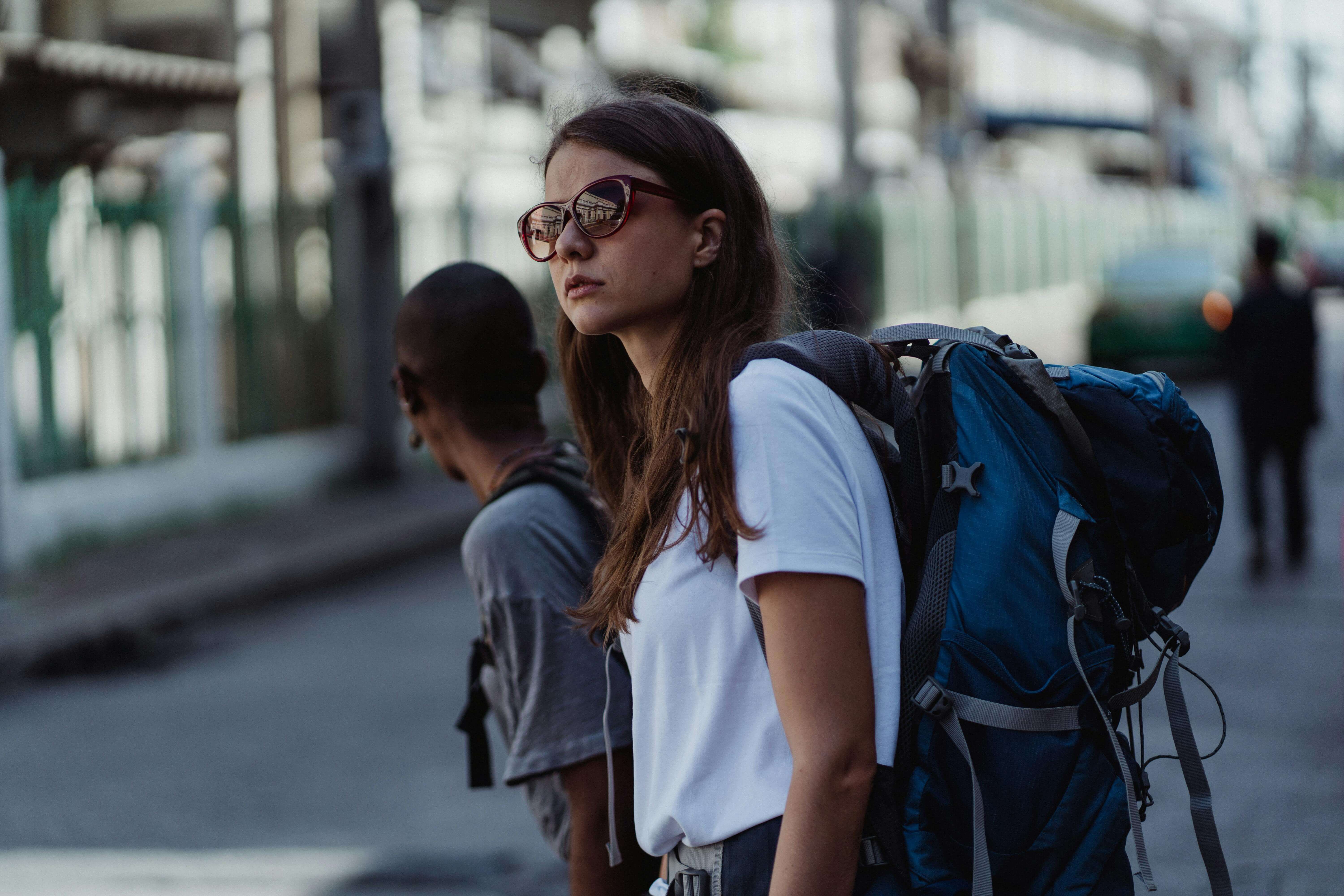 woman with large backpack and sunglasses waiting at a city street | expat relationship problems | international therapist | England | France