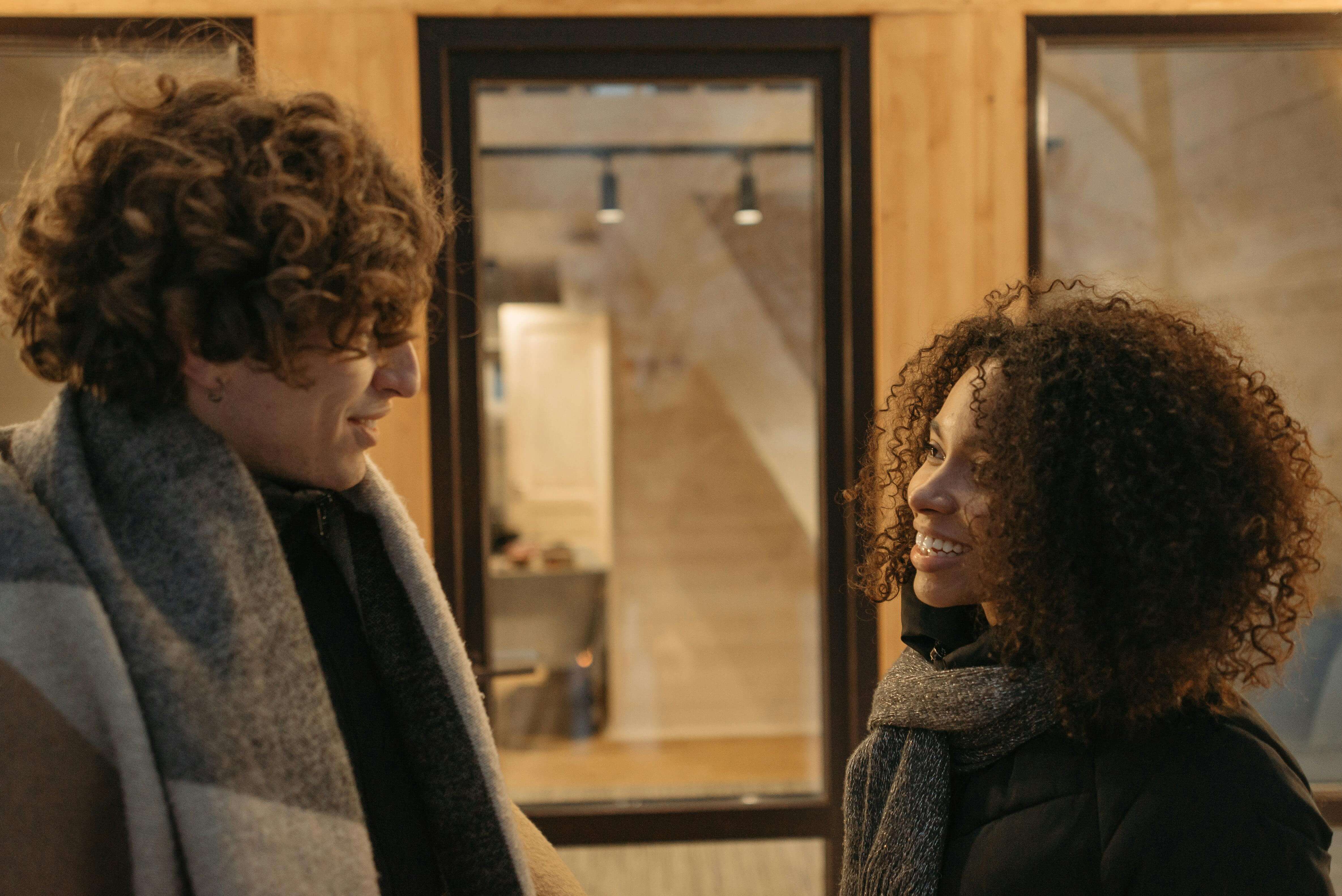 a man and woman with curly hair smiling and talking together outside a warmly lit building | expat commitment issues | international therapy and coaching | Netherlands | China