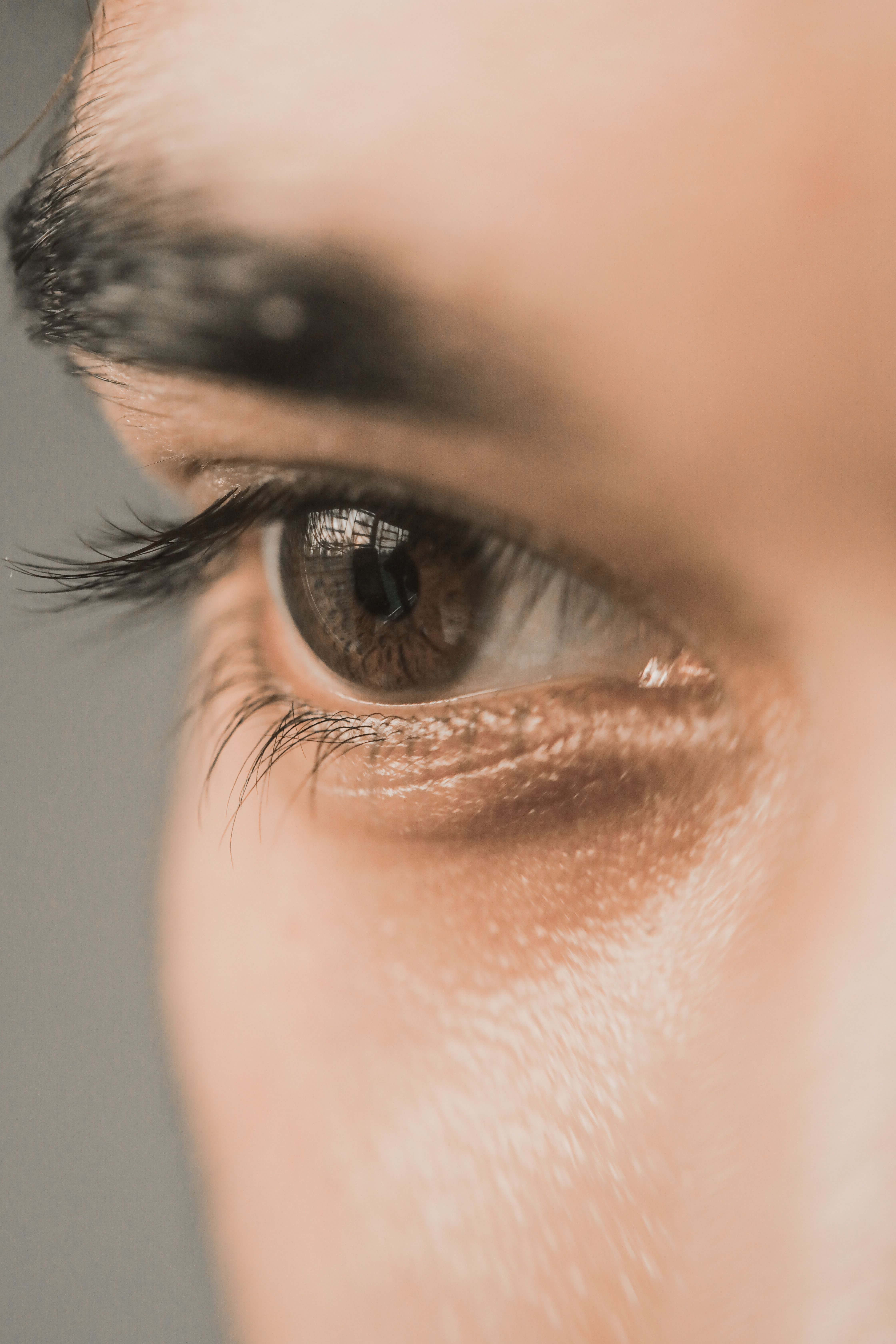 Extreme close up of a person's brown eye with long lashes against a soft grey background | what is EMDR | EMDR for trauma online | EMDR therapist online | Germany | Portugal | Scotland