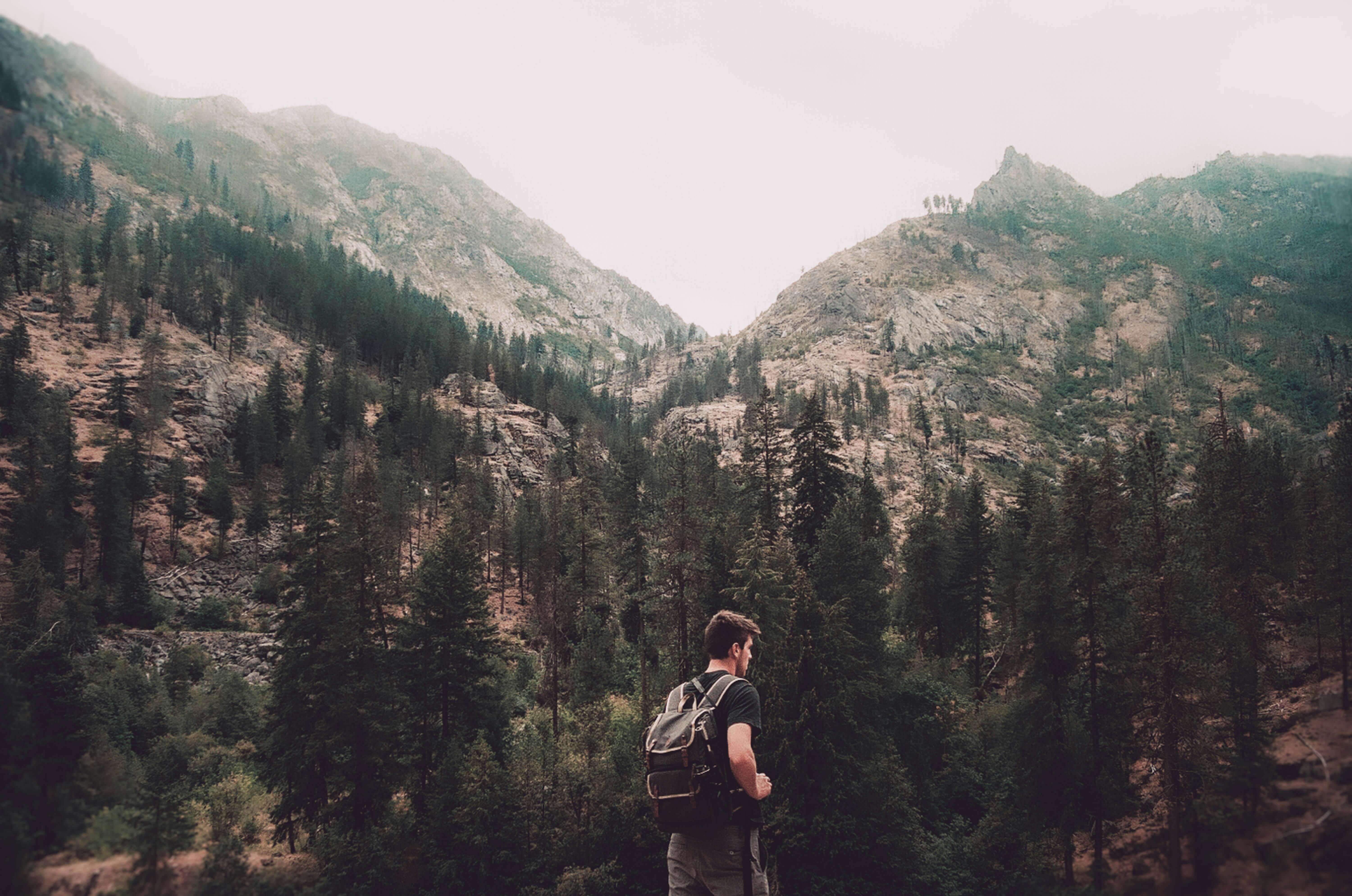 man with a backpack standing in a mountain range | therapy for expats wanting roots | international therapist | online therapy while living abroad | Netherlands | England | Italy