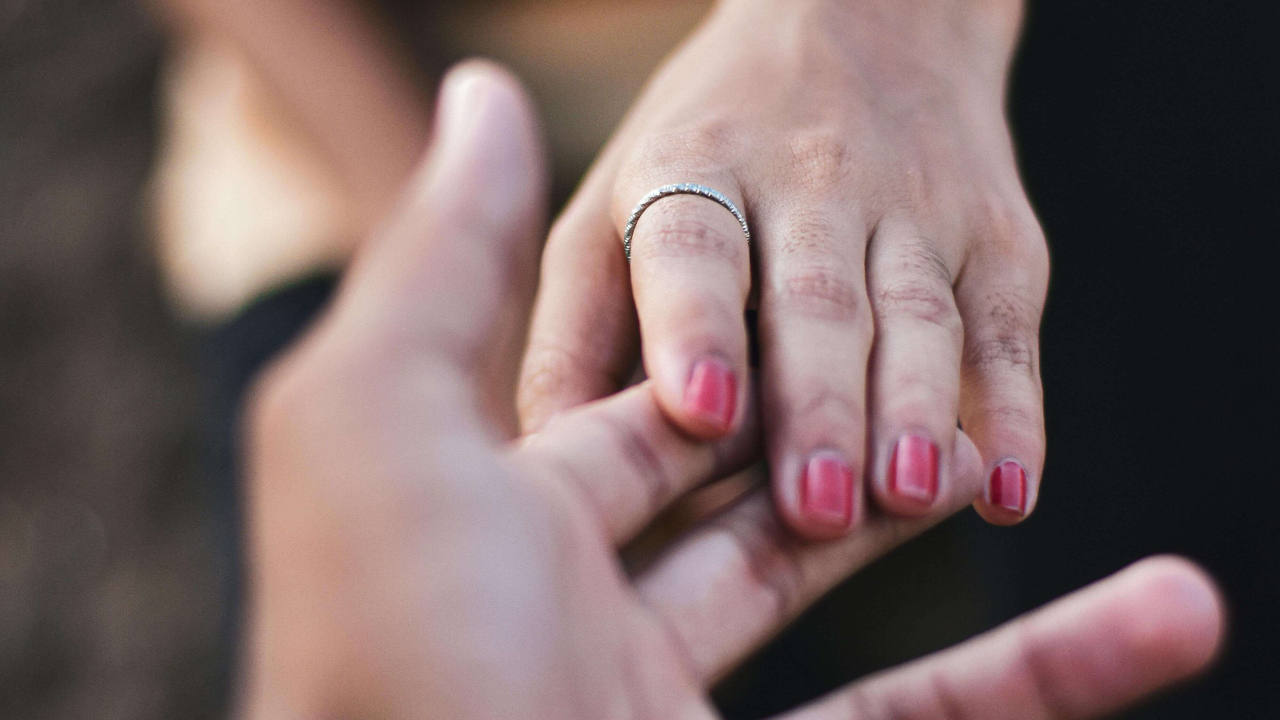 Close up of two people reaching toward each other's hands both wearing rings | attachment wounds expat | expat intimacy | international therapist | Italy | Japan