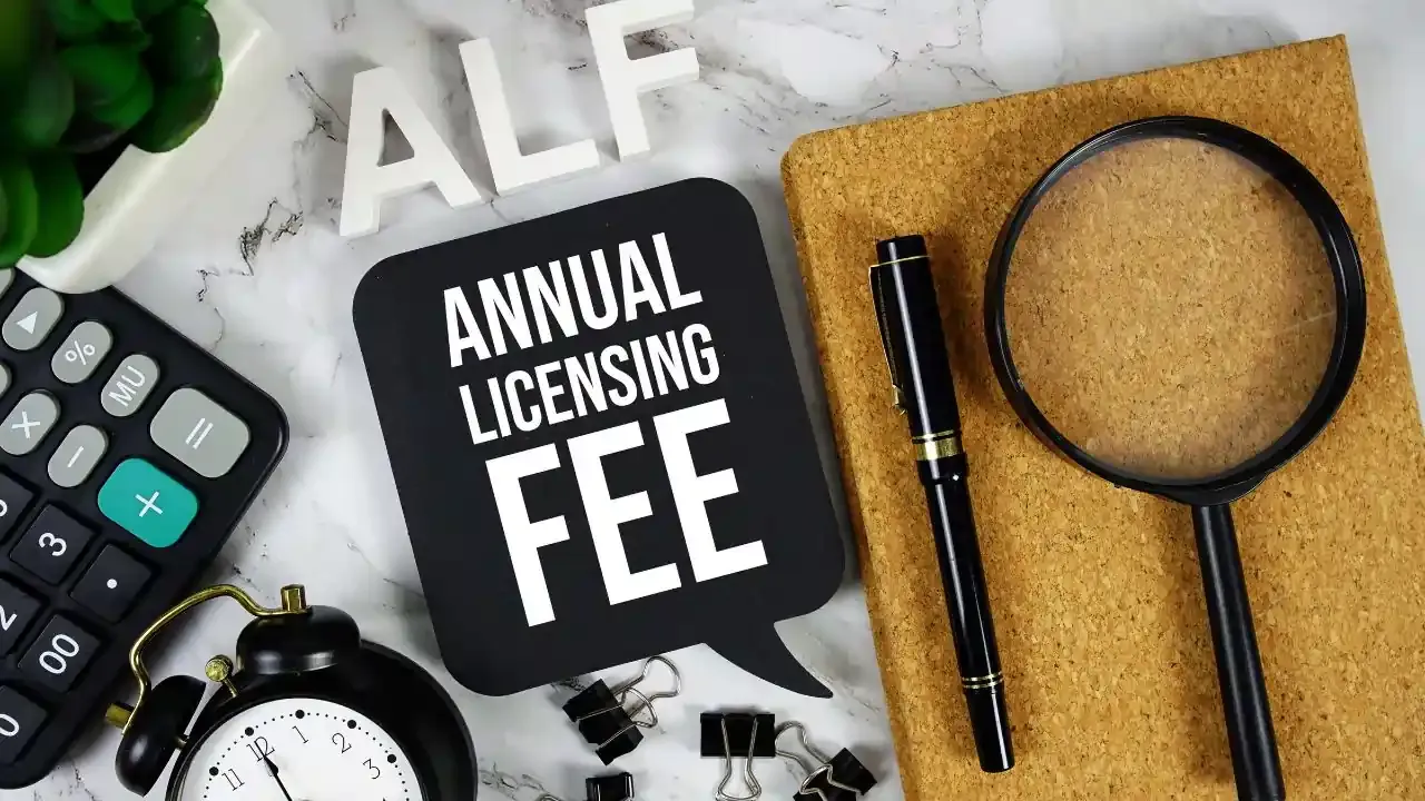 A table with various stationery, a magnifying glass, and the words Annual Licensing Fee