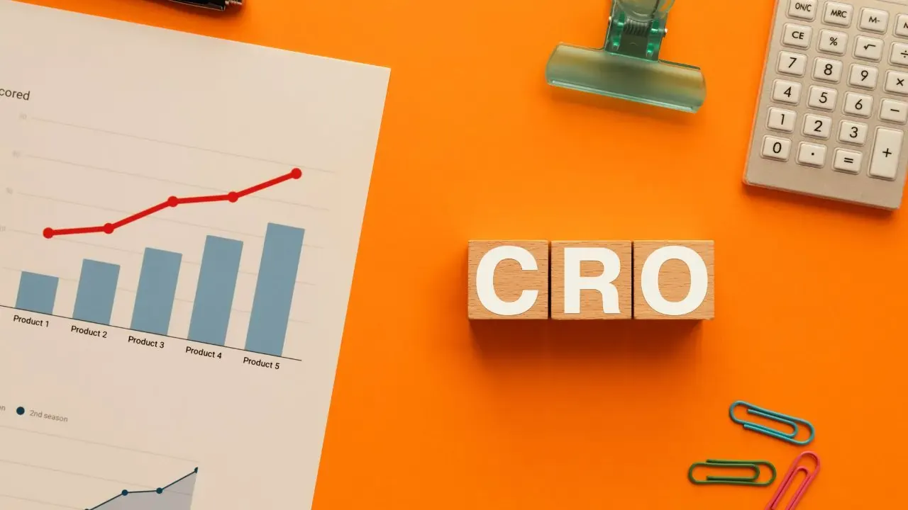 An orange tables with various papers, a calculator, and wooden cubes spelling out CRO