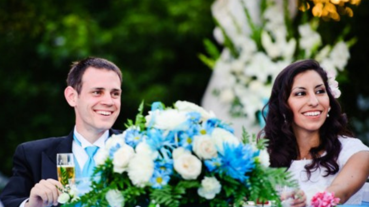 Bride and groom smiling during wedding reception while listening to a heartfelt toast, representing how to write an LDS wedding speech.