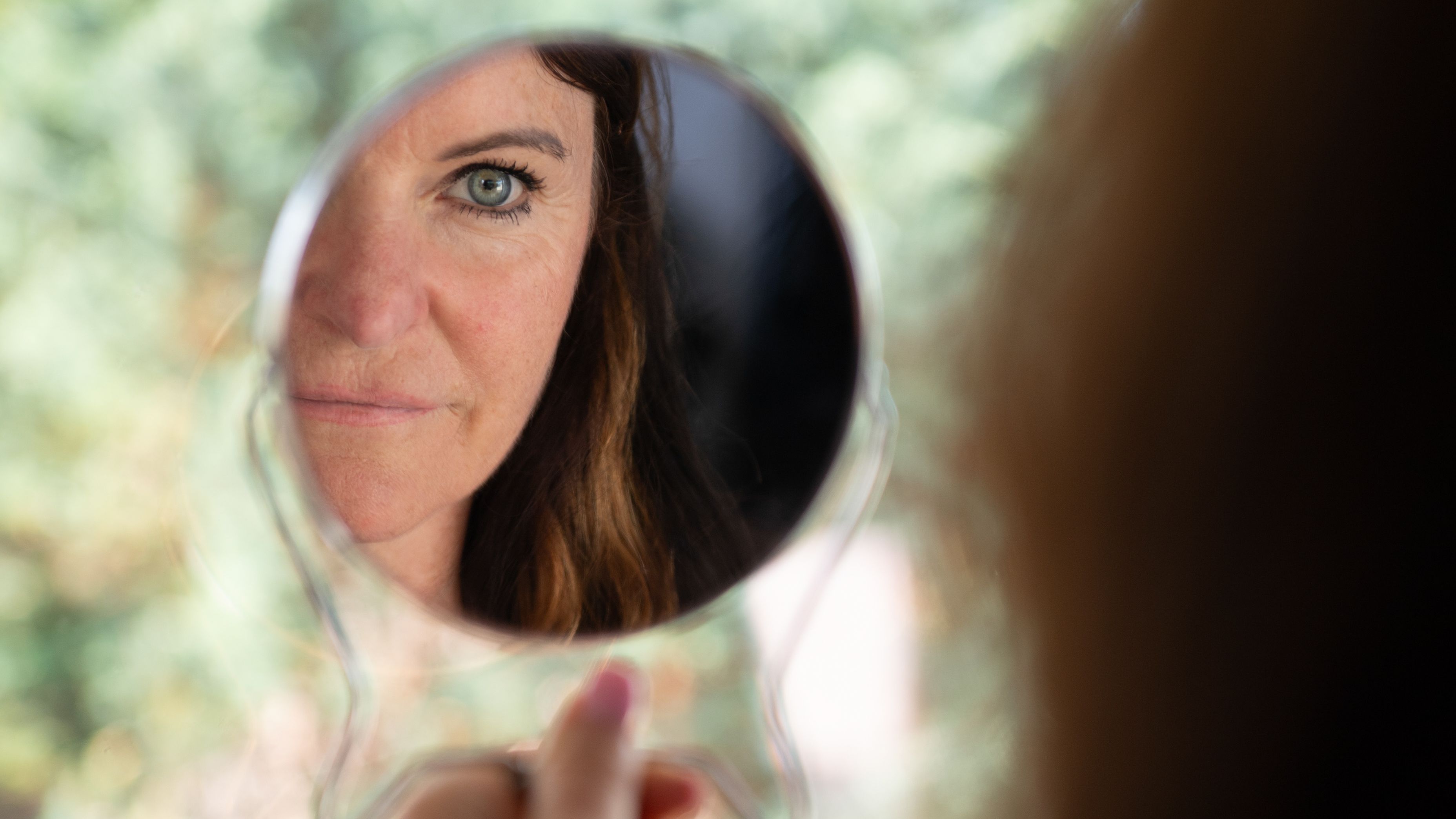 Kvinne som ser på sitt eget speilbilde, symbol på selvrefleksjon og egenverdi