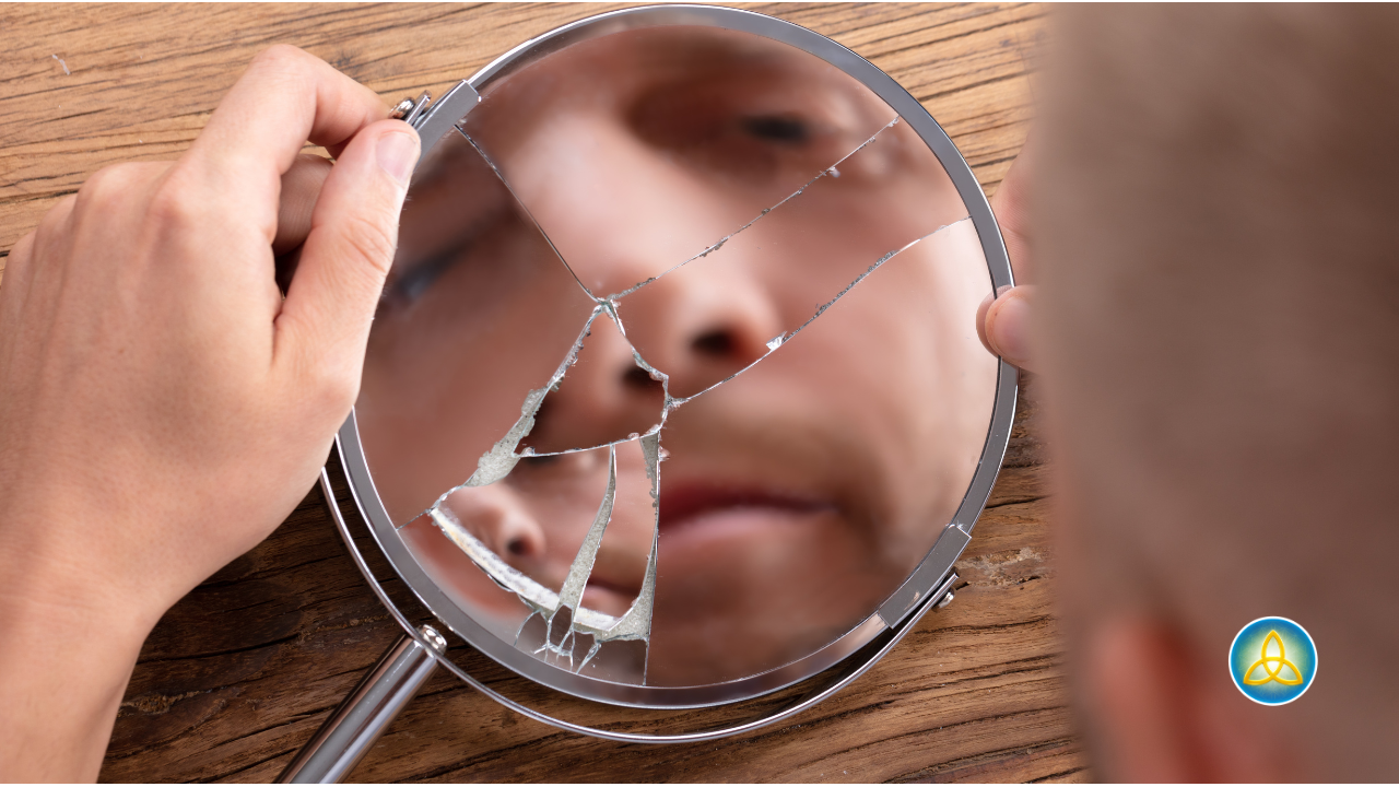 Man looking into broken mirror, symbolizing self-reflection and fragmented identity after intimate partner violence.