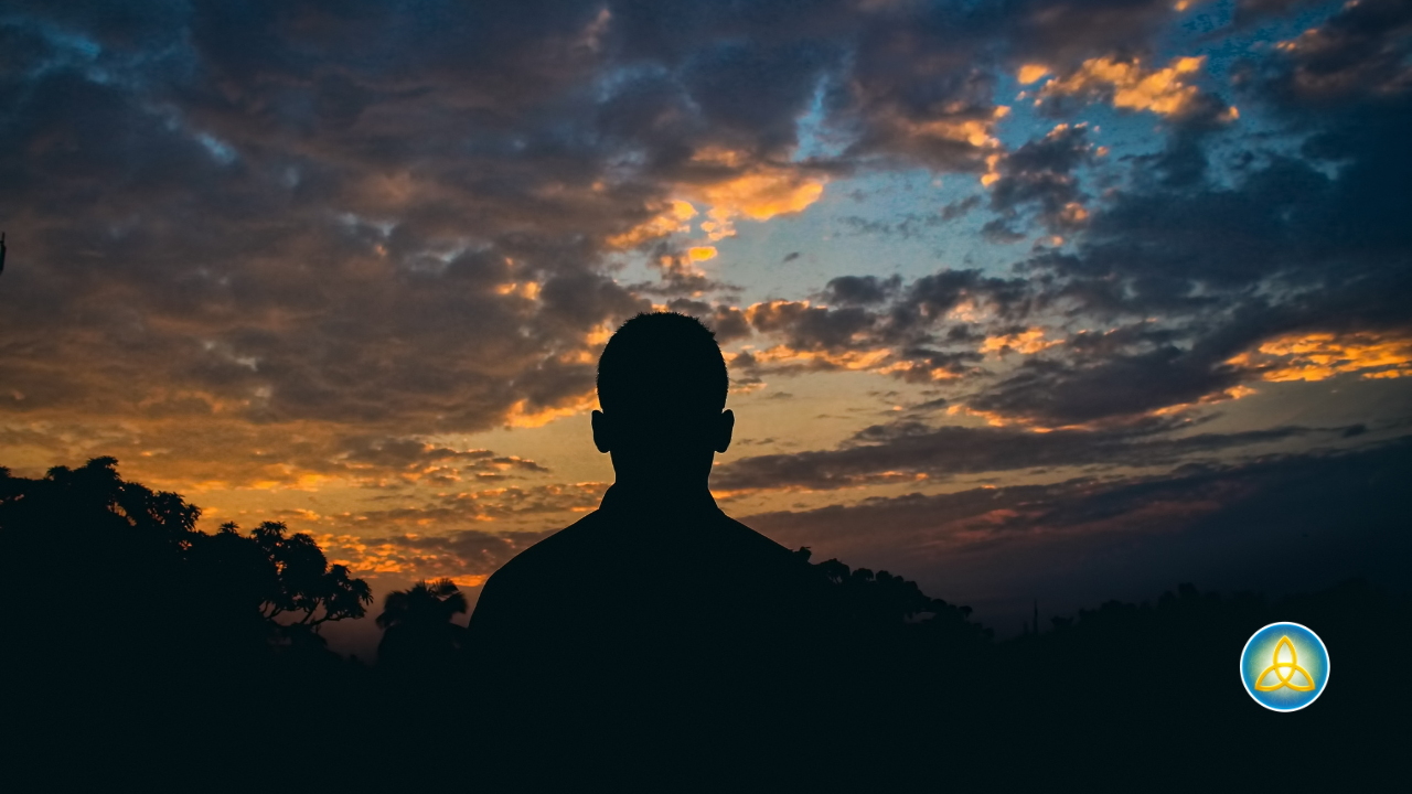 Silhouette of a man seen from behind, looking out at a dramatic sunset sky shifting from golden to deep blue, representing the contemplation and inner reckoning men face going through divorce