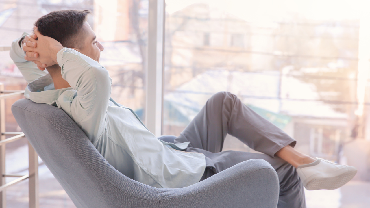 Man relaxing in a chair and looking through a window on a sunny day